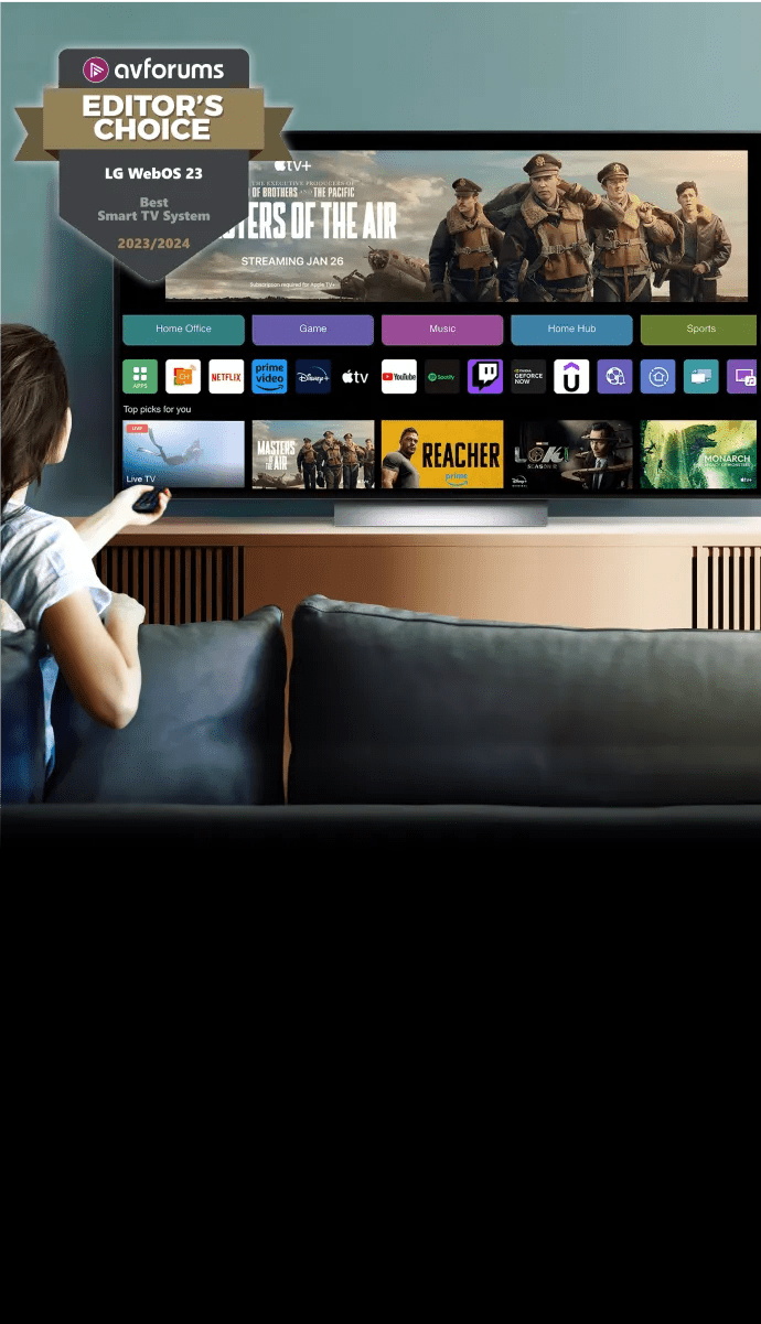 A woman relaxes on a couch, watching a TV screen that features a streaming application.