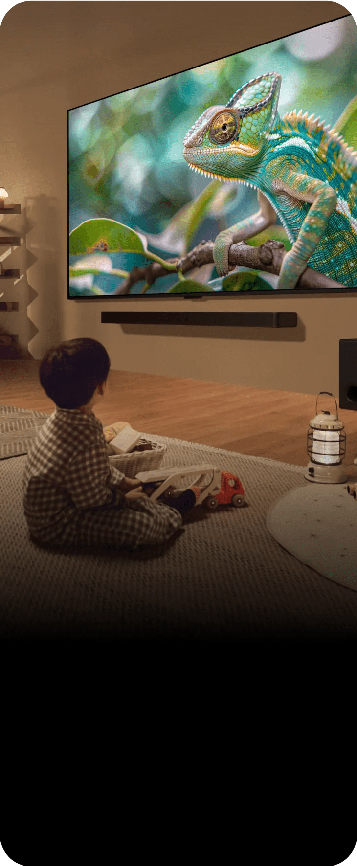 A child sits on the floor, captivated by a movie playing on the television in a cozy living room setting.