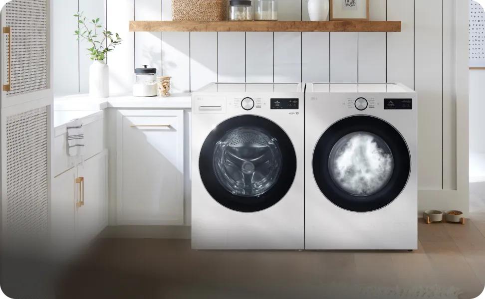 A white LG front load washer and white front load LG dryer sit next to each other in a white-accented laundry room. The dryer's window is filled with steam.
